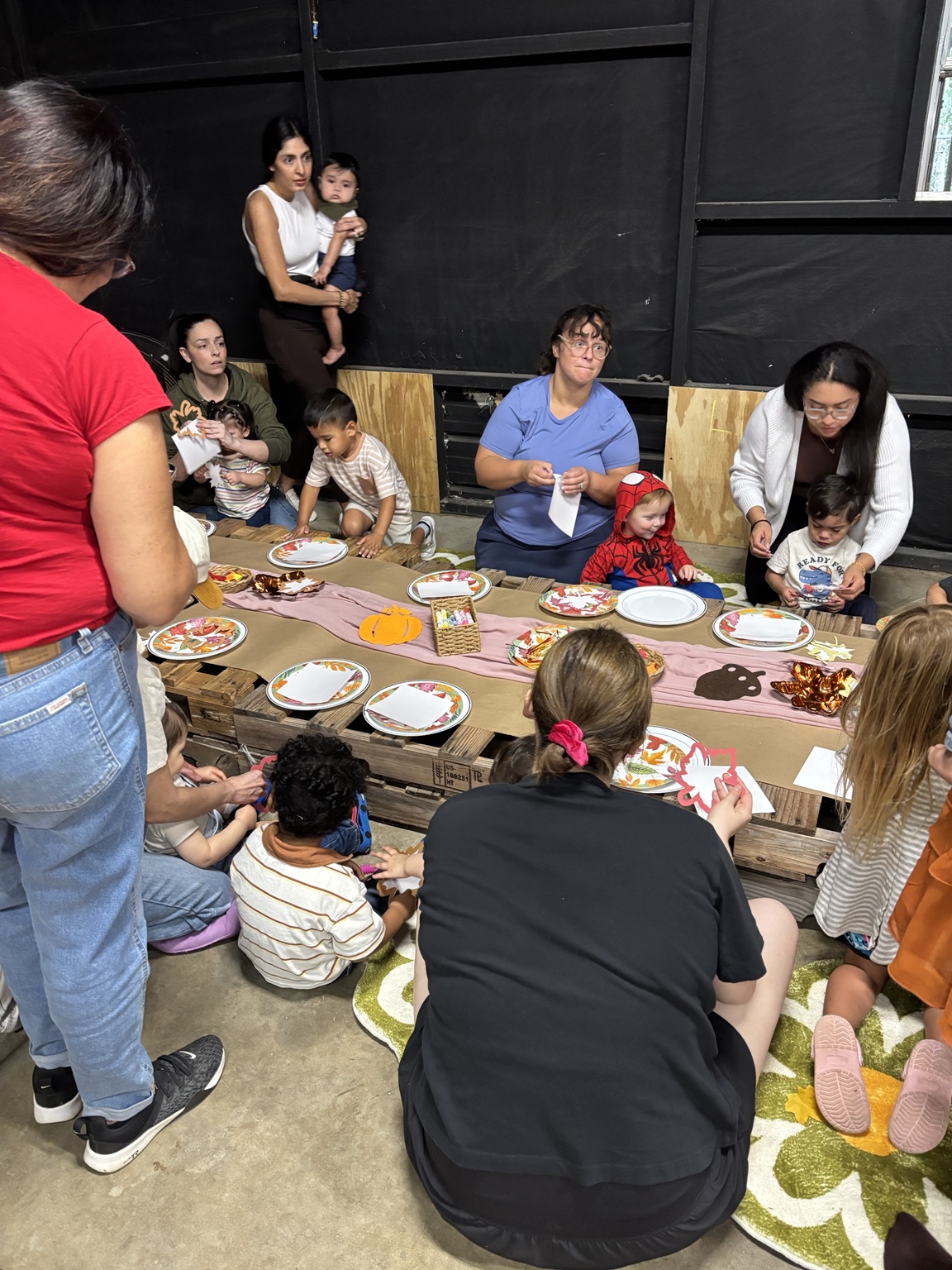 Children and caregivers sharing a fall craft activity.